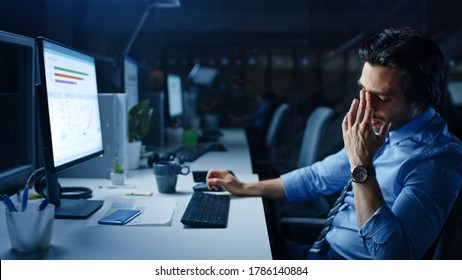 In the Office at Night Overworked Tired Office Worker Uses Desktop Computer Yawning, Drinks Coffee. Tired Exhausted Businessman Finishing Important Project - Powered by Shutterstock