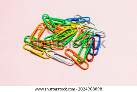 Office paper clips isolated on colored background. Pink, red, blue, green, orange colorful Plastic paperclips documents staple attach tools.