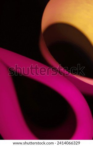 Office paper for printers with folds in the shape of ellipses or drops, with red and yellow light forming an original abstract design of blurred edges towards the black background 
