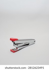 an office paper stapler with red plastic cap isolated in a white background