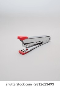 an office paper stapler with red plastic cap isolated in a white background