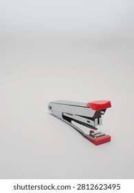 an office paper stapler with red plastic cap isolated in a white background