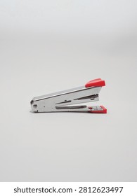 an office paper stapler with red plastic cap isolated in a white background