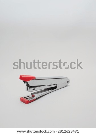 an office paper stapler with red plastic cap isolated in a white background