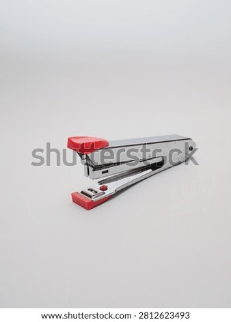 an office paper stapler with red plastic cap isolated in a white background