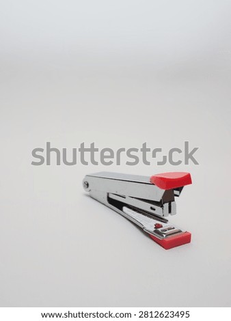 an office paper stapler with red plastic cap isolated in a white background