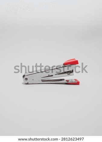 an office paper stapler with red plastic cap isolated in a white background