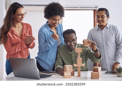 Office, people and happy for teamwork with building blocks for problem solving, solution and educational. Diversity, employees and game with success, celebration and support as graphic designer - Powered by Shutterstock