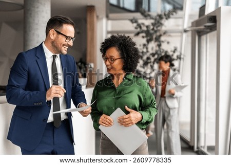 Office professionals engaged in a collaborative discussion, focusing on documents, within a modern corporate environment.