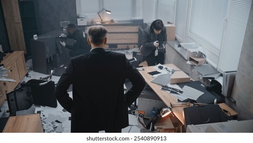 Office robbery case: High angle of detective examining crime scene, female criminalist taking photos of clues, African American policeman looking for fingerprints. Crime investigation team working.