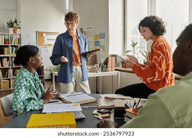 Office setting with diverse team collaborating on project, using various devices. Equally engaged in conversation, brainstorming, and research, fostering a productive atmosphere - Powered by Shutterstock