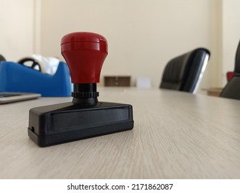 Office Stamp With Black And Red Color On White Table. Blurred Office Environment Background