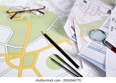 Office Stationery And Eyeglasses On Cadastral Maps Of Territory With Buildings