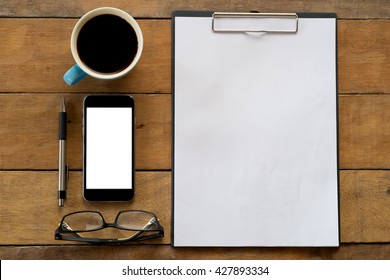 Office Stuff With Blank Paper Over Blackboard, Pen, Smart Phone, Eyeglasses And Cup Of Coffee . Flat Lay Photo.View From Above.Supplies And Gadgets On Office Stuff.Working Desk Table Concept.