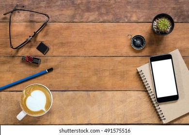 Office stuff with blank screen smart phone, leather notebook, glasses, pencil, flashdrive and cup of coffee. Top view with copy space.Office desk table concept.