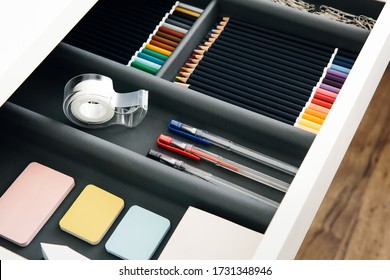 
Office supplies in desktop drawer. Writing pens, pencils, paper clips, color sheets for notes. Workplace order. Work at home.