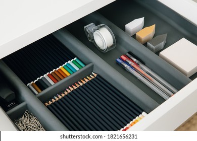 Office supplies in desktop drawer. Writing pens, pencils, paper clips, color sheets for notes. Workplace order. 