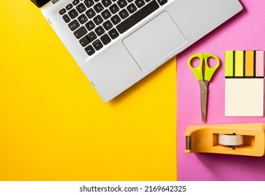 Office Supplies, Next To A Laptop, On A Yellow And Pink Split Background. Concept Of Back To Work In The Office