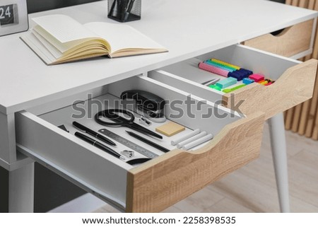 Office supplies in open desk drawers indoors