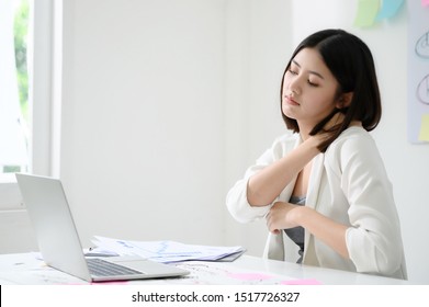 Office syndrome concept. Young asian businesswoman feeling pain in neck after working on computer laptop for a long time