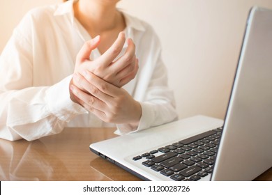 Office syndrome - Young female suffering from hand pain while using laptop at workplace. Occupational risk factor for carpal tunnel syndrome or trigger finger. Health care and medical concept.
