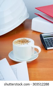 Office table with coffee cup , work essential tools and white hard hat - Shutterstock ID 303512288
