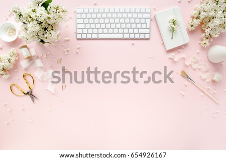 Office table desk with computer, bouquet lilac, clipboard. magazines, social media. Top view. Flat lay. Home office workspace. Women's fashion accessories isolated on pink background. 