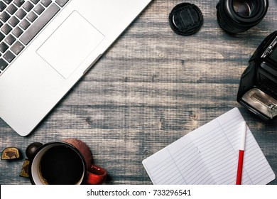 Office table desk, Flat lay. Workspace with laptop, red cup, candy, notebook, lens and flash on wooden background. 