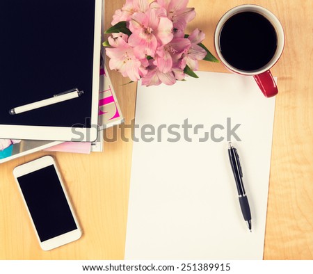 Office table with digital tablet, smartphone empty sheet of paper and cup of coffee. View from above with copy space