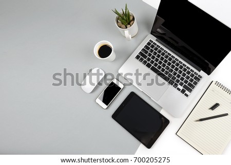 Office table with  laptop computer, notebook, digital tablet and smartphone on modern two tone (white and grey) background.