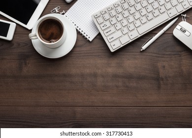 office table with notebook, computer keyboard, mouse, cup of coffee, tablet pc and smartphone. copy space - Powered by Shutterstock