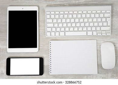 Office table with notebook, computer keyboard and mouse, tablet pc and smartphone