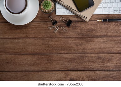 Office table with notebook, computer keyboard, mouse, cup of coffee, tablet pc and smartphone, Top view with copy space on wooden floor