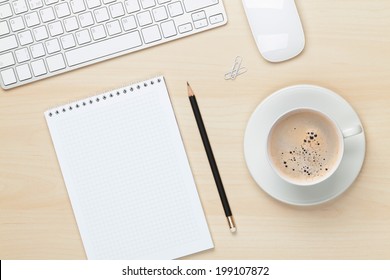 Office table with notepad, computer and coffee cup. View from above