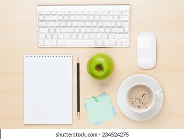 Office table with notepad, computer and coffee cup. View from above
