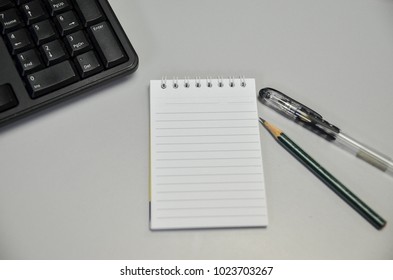 Office table with notepad, computer keyboard, pen. pencil and smartphone. View from above.