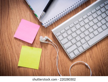 Office table with notepad, computer keyboard, coffee cup  , pen ,headphone , sticky notes. View from above with copy space