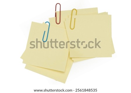 Office table with pen, note papers and paper clips top view. Blank post it note with yellow paper clip isolated on white