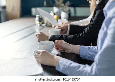 Office Team On A Morning Meeting At The Work Discussing Problems From A Cup Of Coffe, Tea. Closeup.