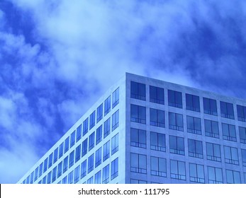 Office windows in front of partially cloudy sky.  Tinted blue.  Plenty of room for text.
