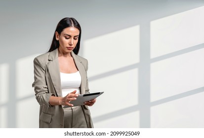 Office woman in beige suit concentrated, working with device. Office company and staff. Copy space blank wall. Concept of boss and management - Shutterstock ID 2099925049