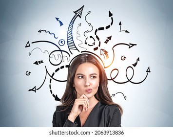 Office woman in black jacket thinking hard, hand to chin. Black arrows drawn on blue wall, multiple direction. Concept of decision making and career development - Powered by Shutterstock