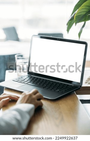 Office work. Computer mockup. Digital technology. Unrecognizable woman working laptop with blank screen in light room interior.