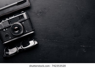 Office work space with camera, notebook, eyepieces, and pen. On a wooden surface. Top view. Free space for your text.