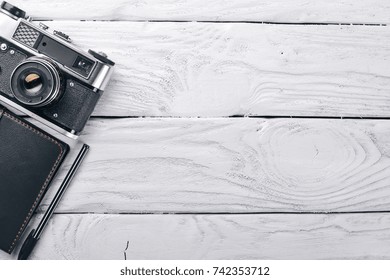 Office work space with camera, notebook, eyepieces, and pen. On a wooden surface. Top view. Free space for your text.