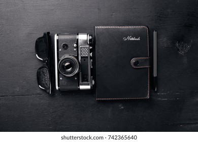 Office work space with camera, notebook, eyepieces, and pen. On a wooden surface. Top view. Free space for your text.