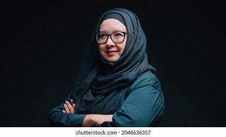 An Office Worker For An Asian Muslim Woman Stands With Arms Crossed With A Happy Face And A Commitment To Work, On Black Background.