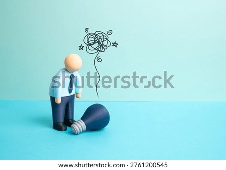 An office worker bends over a burned-out lightbulb with an idea fading. Burnout reduces creativity and innovation. Workplace stress challenges productivity and mental resilience in modern jobs