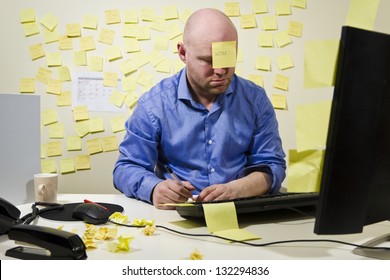 Office worker / businessman with too much work to do. Many notes in the background and one post-it at the forehead.