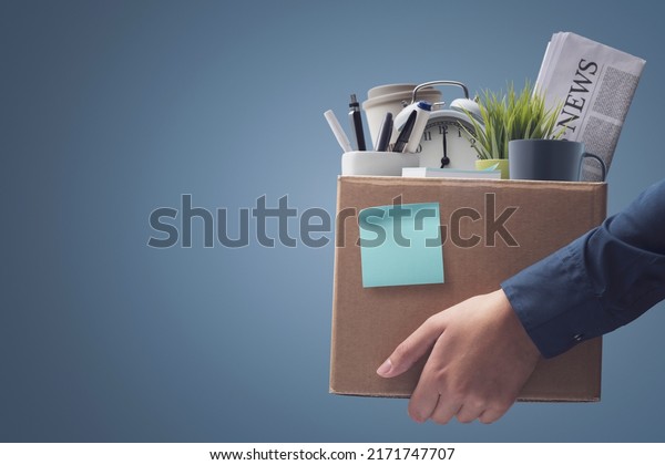 Office worker carrying\
personal belongings in a box after being fired, unemployment and\
career concept